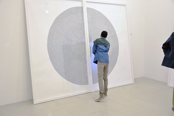A viewer looking at ‘Circle of Uncertainty (6)’, from a series of drawings by Dana Whabira exhibited in the Zimbabwe Pavilion, at the 57th Venice Biennale 2017, entitled “Deconstructing Boundaries: Exploring Ideas of Belonging” curated by Raphael Chikukwa..